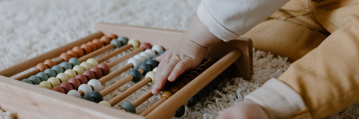 Baby with abacus. Life Charity asks - Free childcare, but ta what cost?