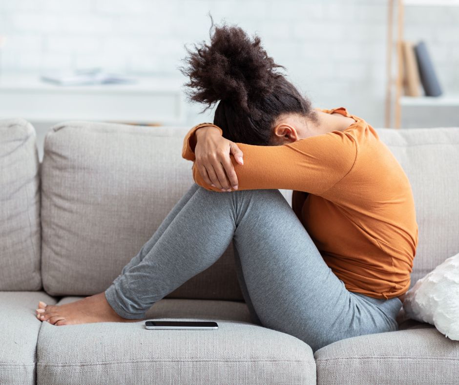 Young woman on couch, sad