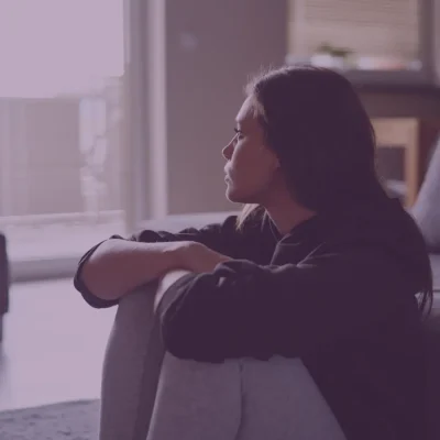 Young woman sat on floor looking out window