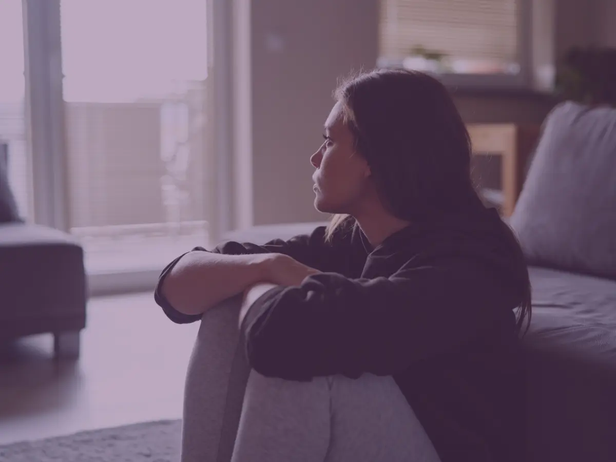Young woman sat on floor looking out window
